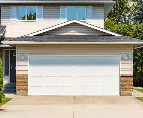 Two-story house with a white garage door and a well-maintained driveway.