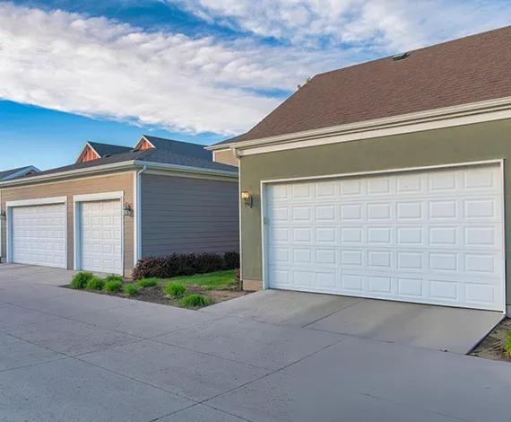 A row of townhomes with attached garages, featuring beige and blue exteriors.