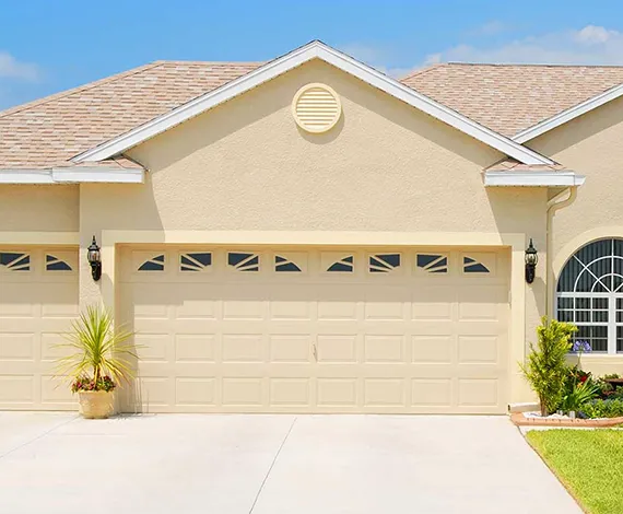 A modern home with a light yellow garage door and a neatly trimmed front lawn.