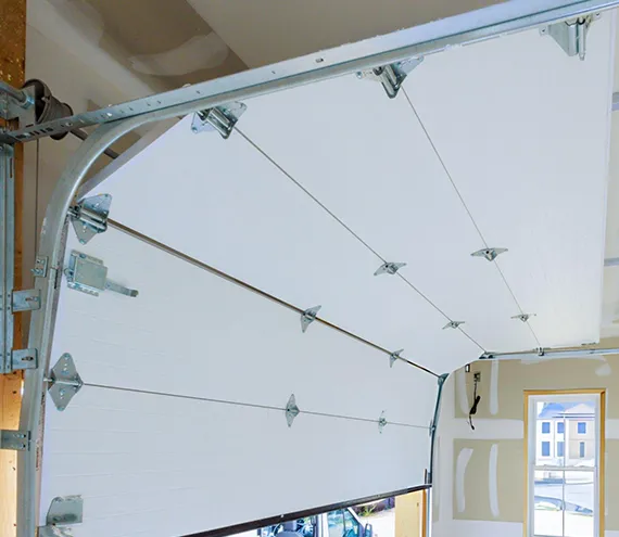 Interior view of a white garage door with a curved track system in a well-lit garage.