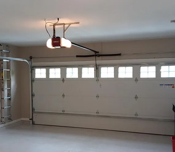 A spacious garage with multiple white-panel doors and an overhead ceiling fan.