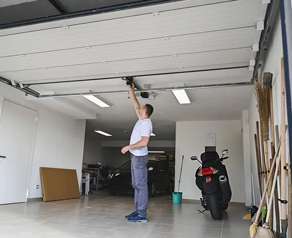 A garage technician standing inside a garage, inspecting a partially open garage door.