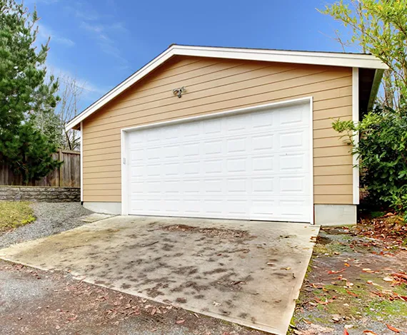 A newly installed white garage door on a residential property with a paved driveway.