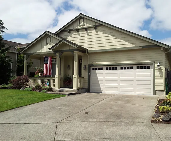A suburban home with a newly installed beige garage door and a well-maintained front yard.
