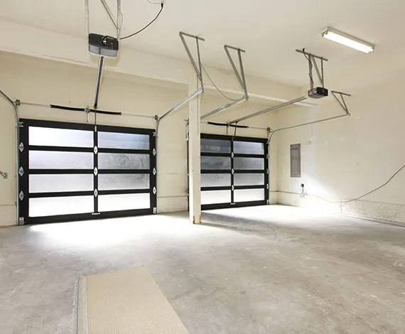 A well-lit, spacious garage with glass-paneled garage doors and a polished concrete floor.